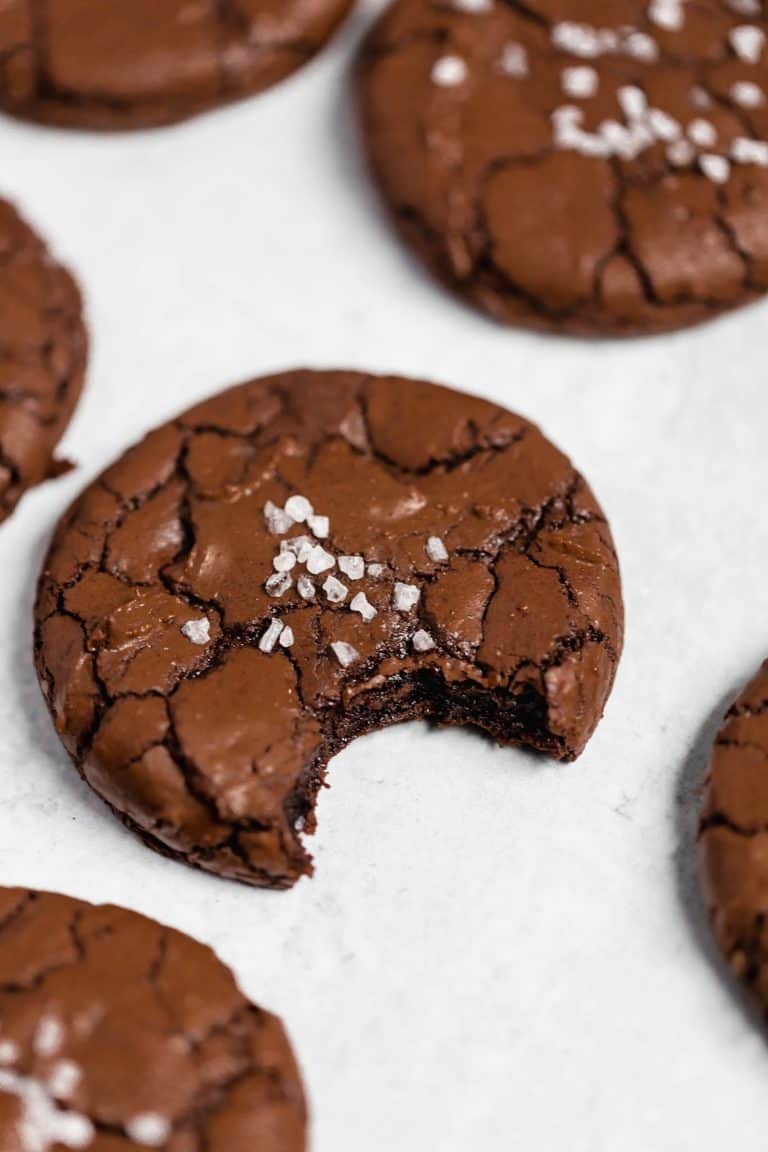 Buttery chocolate cookies with a cracked surface and a sprinkle of sea salt, close-up image showing rich chocolate interior and crispy exterior, perfect for chocolate lovers.