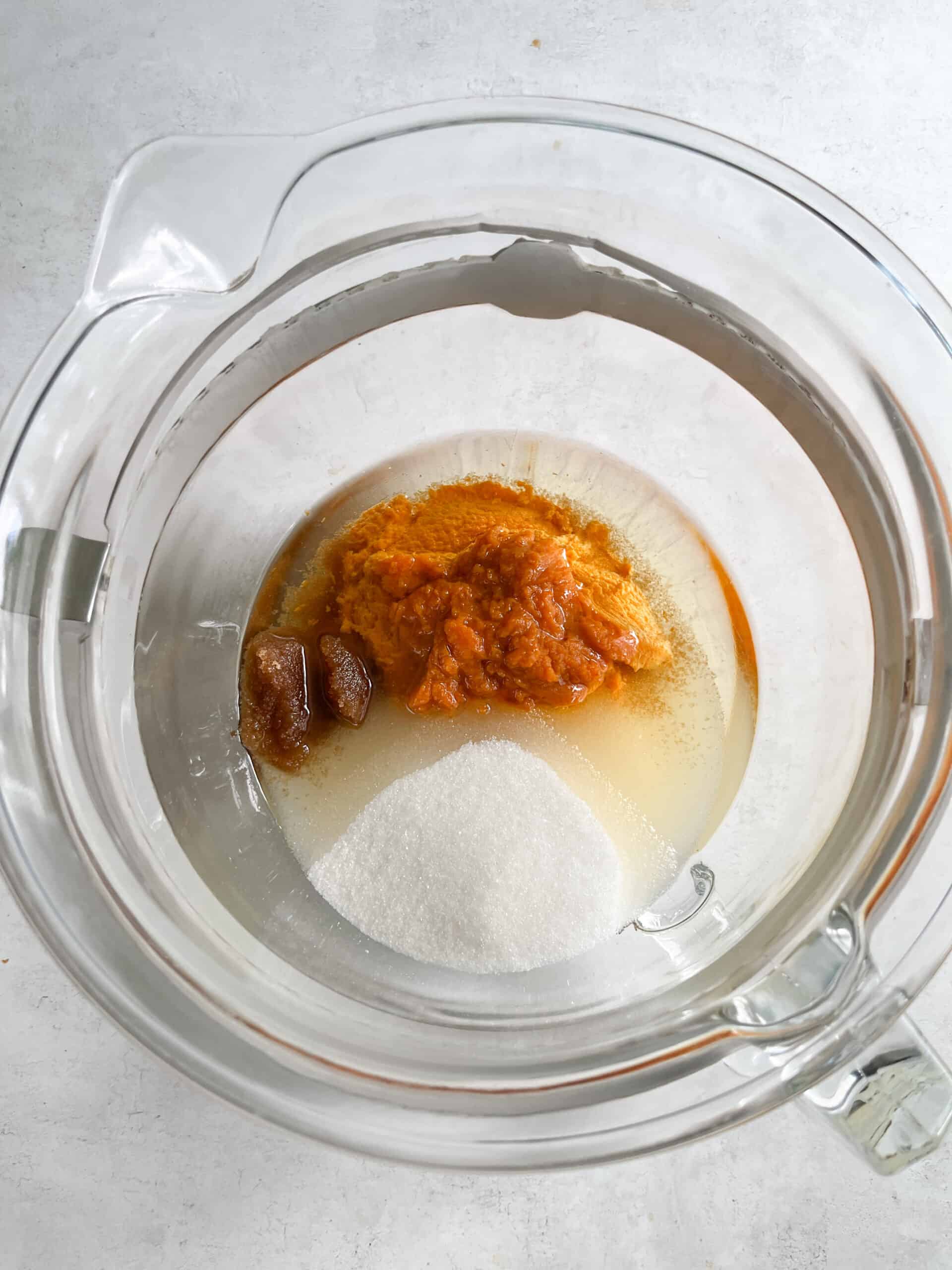 Sweetsherrypie.com, pumpkin pie filling ingredients in a glass mixing bowl, including pumpkin, sugar, and spices, ready for baking, with a focus on homemade pie preparation.