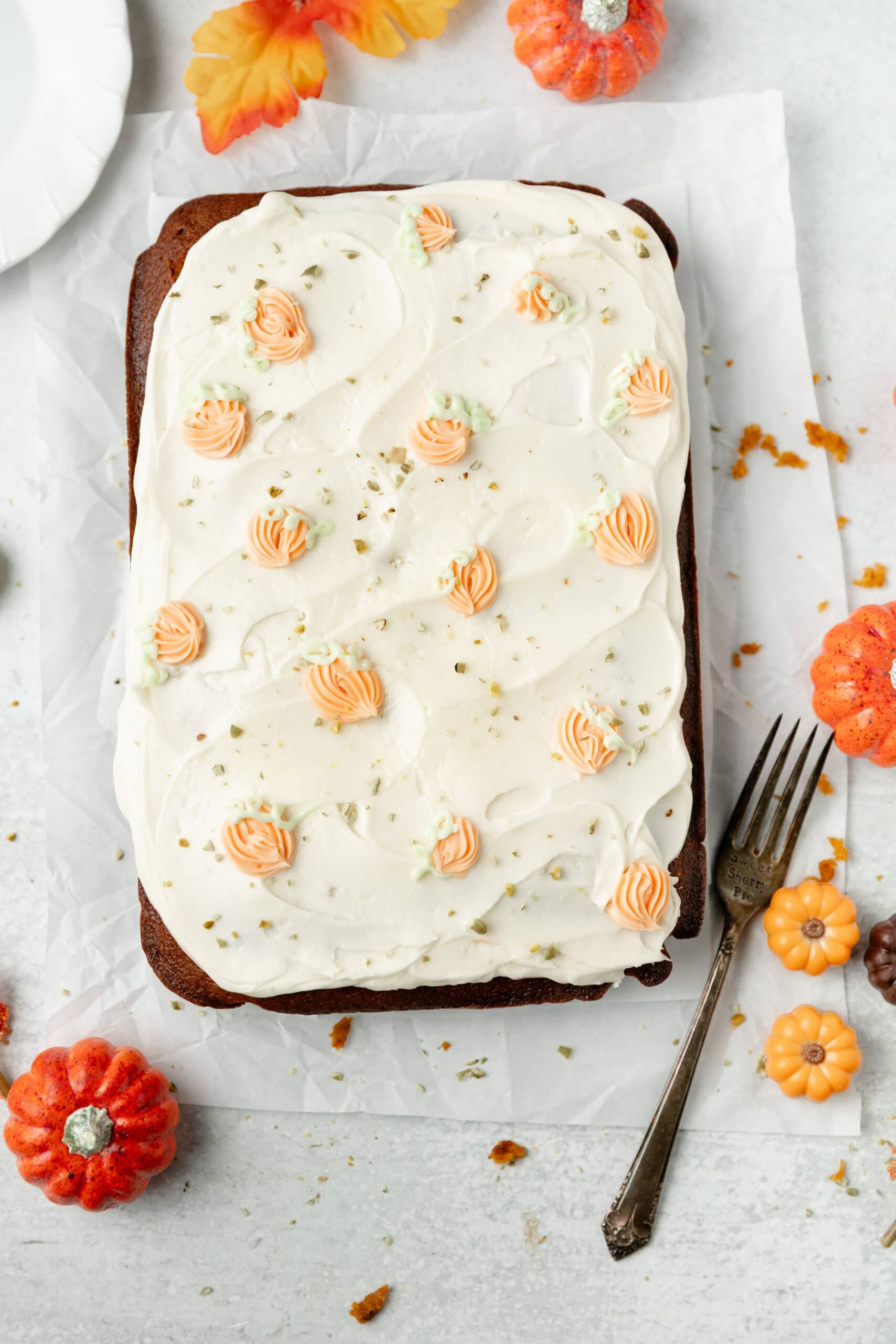 Cream cheese pumpkin sheet cake with fall pumpkin decorations and whipped frosting, perfect for autumn celebrations. Moist, delicious pumpkin cake topped with cream cheese frosting and edible pumpkin accents.