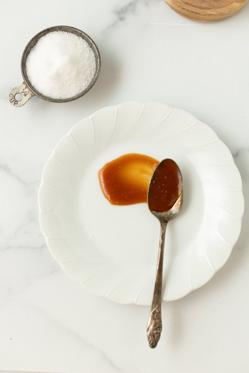 Sweetsherrypie.com, sugar and caramel sauce on a white plate with a spoon.